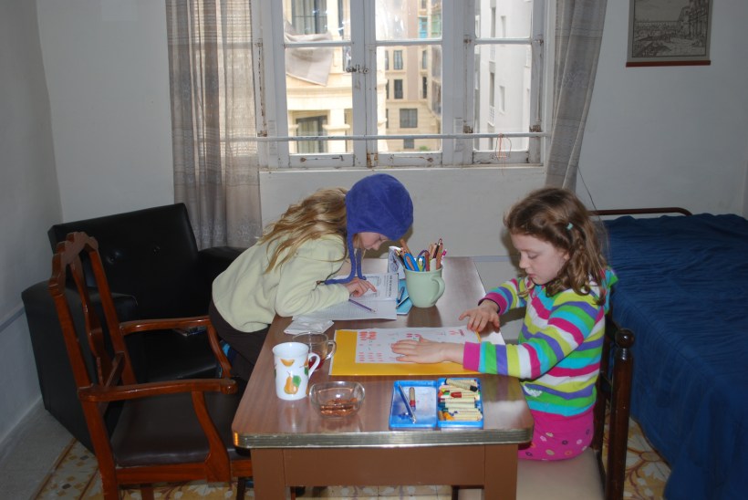 When we return to our flat, the Sylvia writes in her weather journal and Lily puts a fruit on her weather tree.  Then it's down to business.  Lily is working on a math unit and Sylvia started a long Language Arts unit.  They do most of their work at this table in the guest bedroom because it has the most natural light.